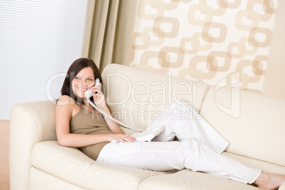 On the phone home - Smiling woman on sofa calling