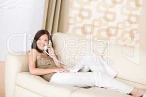 On the phone home - Smiling woman on sofa calling