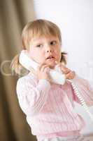 Little girl holding telephone receiver calling