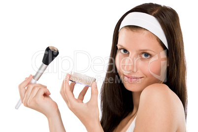 Beautiful woman applying powder with brush