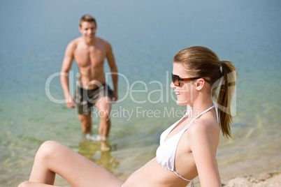 Couple on beach - woman in bikini sunbathing