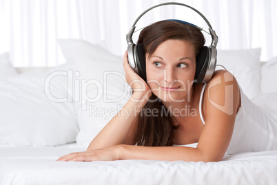 Happy woman listening to music lying on sofa