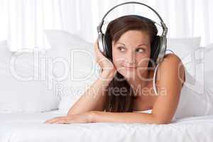 Happy woman listening to music lying on sofa