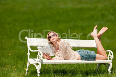 Spring - Young woman relaxing on bench in meadow