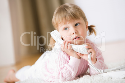 Little girl lying down on carpet with phone calling