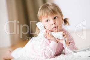 Little girl lying down on carpet with phone calling