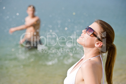 Couple on beach - woman in bikini sunbathing