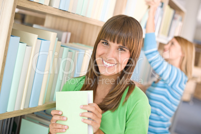 Student in library - two woman hold book