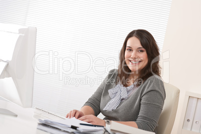 Happy businesswoman sitting at office desk