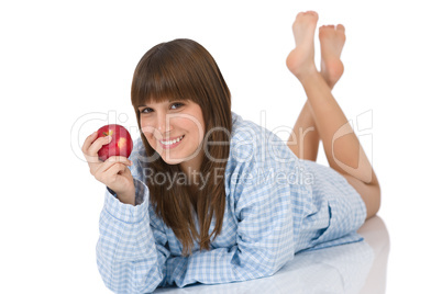 Happy teenager in pajamas eating healthy apple