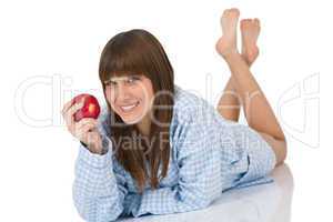 Happy teenager in pajamas eating healthy apple