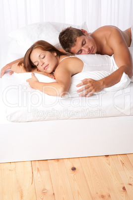 Young man and woman lying down in white bed