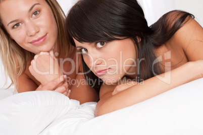 Blond woman and brunette having fun in bed