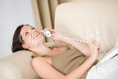 On the phone home: Smiling woman lying down on sofa calling