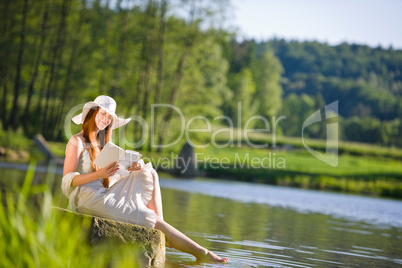 Long red hair romantic woman relax by lake with book