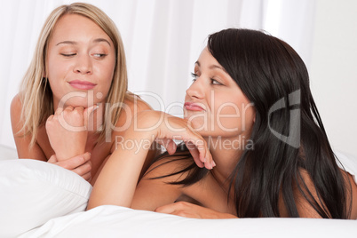 Blond woman and brunette having fun in bed