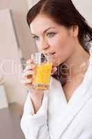 Young woman drink orange juice in kitchen