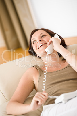 On the phone home: Smiling woman on sofa calling