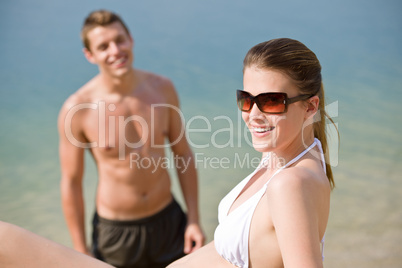 Couple on beach - woman in bikini sunbathing