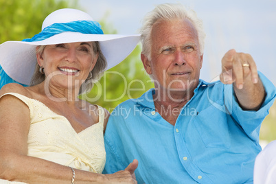 Happy Senior Couple Pointing To Sea on A Tropical Beach