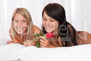 Two young smiling women naked in bed