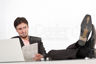Successful modern businessman with laptop and newspaper