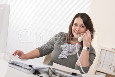 Smiling young woman on the phone at office