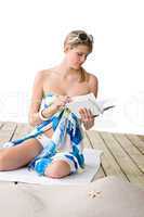 Beach - woman sitting with book, sunbathing