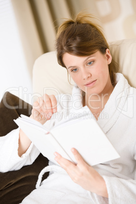 Young woman read book sitting on sofa