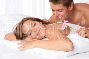 Happy man and woman lying down in bed together