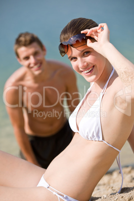 Couple on beach - woman in bikini sunbathing