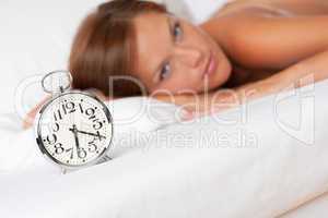 White lounge - Alarm clock standing on bed, woman in background