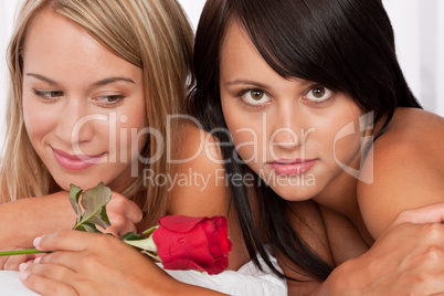 Close-up of two young naked woman with red rose