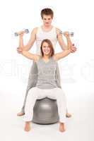 Young couple with weights and fitness ball on white