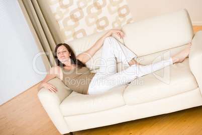 Young happy woman relax lying down on sofa