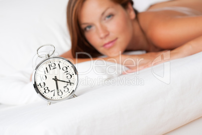 White lounge - Alarm clock standing on bed, woman in background