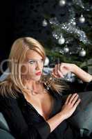 Portrait of blond sexy woman in black dress on Christmas in fron