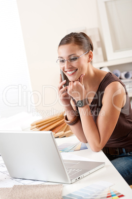 Young female designer on the phone with laptop