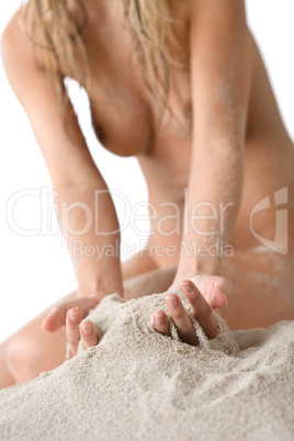Naked woman sunbathing on beach holding sand