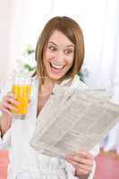 Breakfast - excited woman reading newspaper drink orange juice
