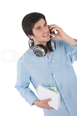 Male student calling with mobile phone holding books