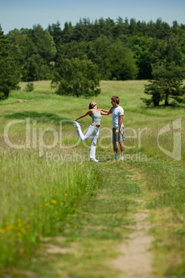 Young man and woman exercising in spring meadow