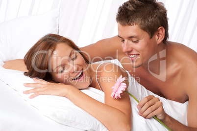 Happy man and woman lying down in bed together