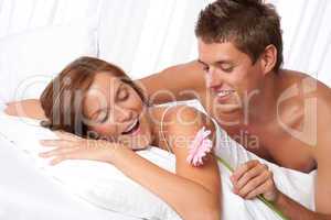 Happy man and woman lying down in bed together