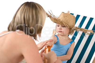 Mother with child apply suntan lotion on beach