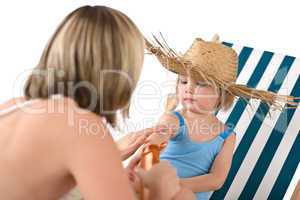 Mother with child apply suntan lotion on beach