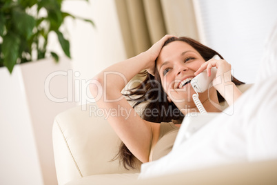 On the phone home: Smiling woman lying down on sofa calling