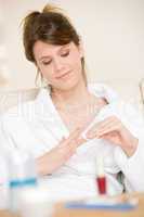 Body care - woman remove nail polish in bathrobe
