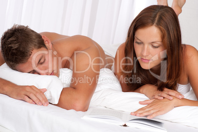 Young man and woman lying down together on white sofa
