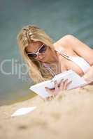 Blond woman in bikini relax on beach with book